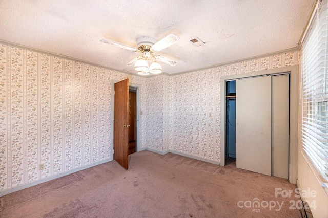 unfurnished bedroom with multiple windows, a textured ceiling, carpet floors, and ceiling fan