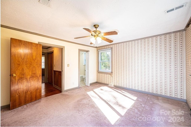 carpeted empty room featuring crown molding, a textured ceiling, and ceiling fan