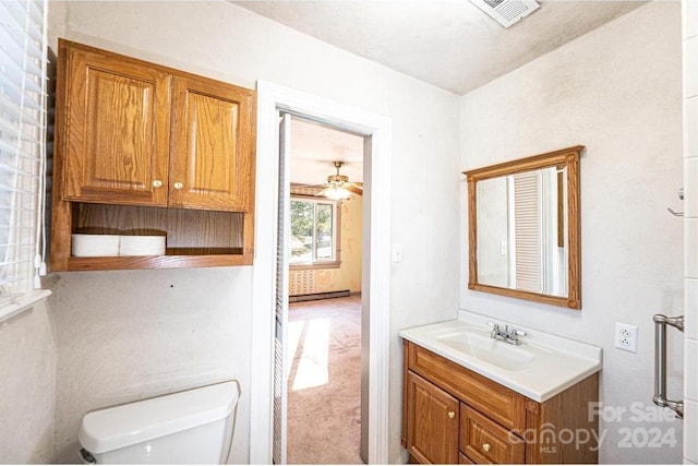 bathroom featuring vanity, toilet, baseboard heating, and ceiling fan