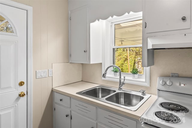 kitchen featuring a healthy amount of sunlight, white cabinetry, white range oven, and sink