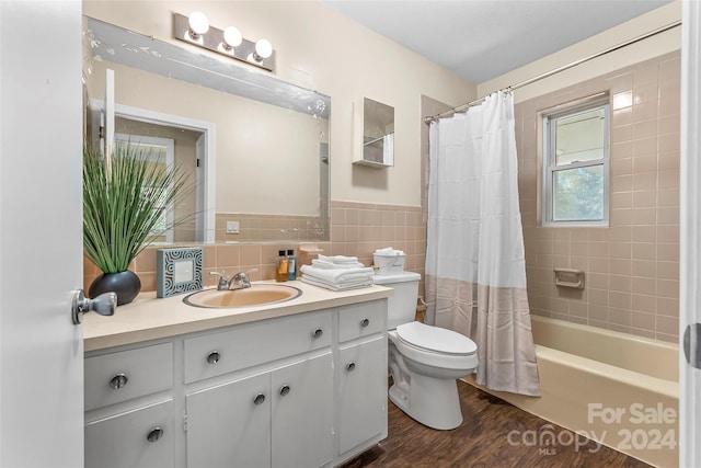 full bathroom featuring wood-type flooring, shower / bath combo with shower curtain, toilet, tile walls, and vanity