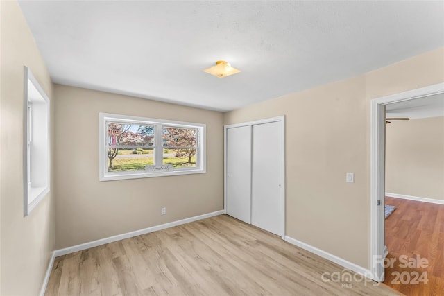 unfurnished bedroom with light hardwood / wood-style flooring and a closet