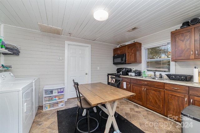 kitchen with wood walls, black appliances, sink, separate washer and dryer, and wooden ceiling