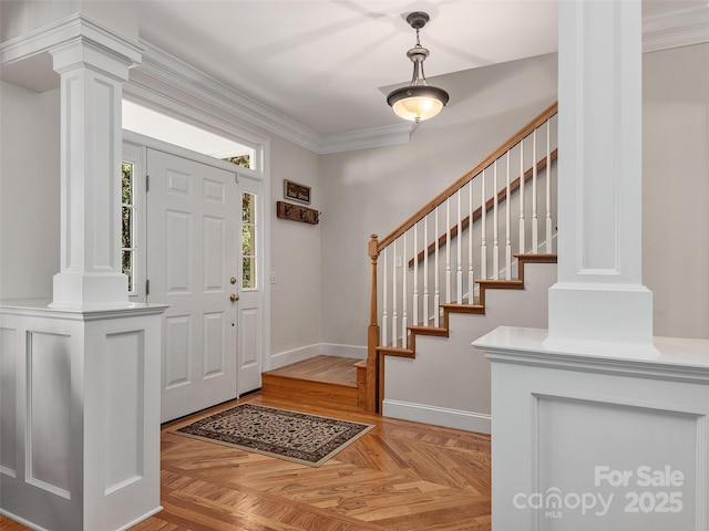 foyer entrance featuring crown molding, light parquet flooring, and decorative columns