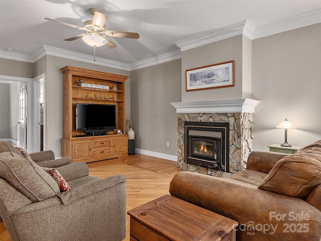 living area featuring baseboards, a fireplace, ceiling fan, light wood-style floors, and crown molding