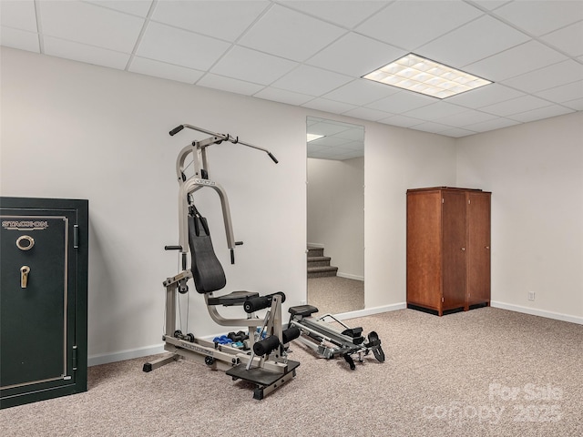 workout area featuring carpet flooring, a paneled ceiling, and baseboards