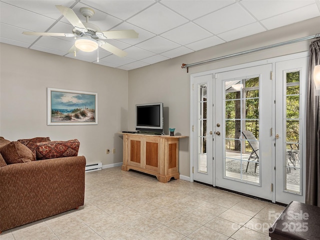 living area with a ceiling fan, a paneled ceiling, baseboards, and a baseboard radiator