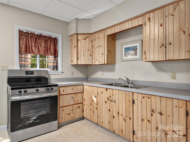 kitchen with light brown cabinetry, a sink, stainless steel electric range, light countertops, and a paneled ceiling