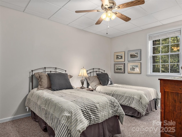 bedroom featuring a drop ceiling, carpet floors, baseboards, and ceiling fan