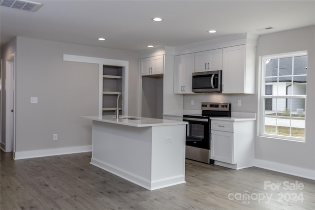 kitchen with white cabinets, a center island with sink, sink, and appliances with stainless steel finishes