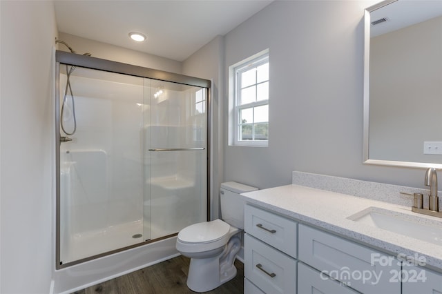 bathroom with walk in shower, vanity, toilet, and wood-type flooring