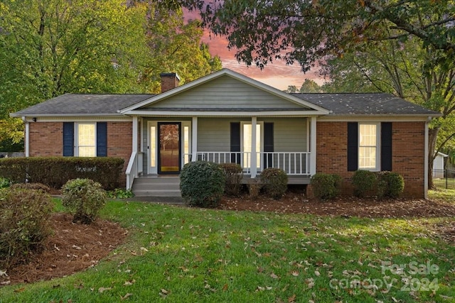 view of front facade featuring covered porch and a yard