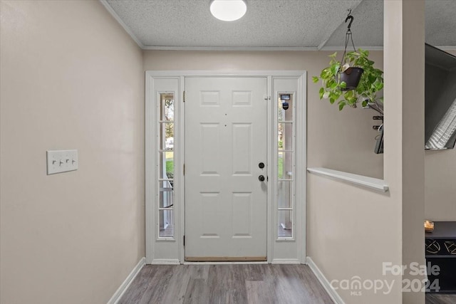 entryway featuring a textured ceiling, light hardwood / wood-style floors, and crown molding