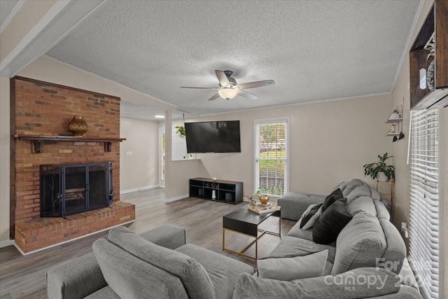 living room with ceiling fan, a fireplace, vaulted ceiling, and light wood-type flooring