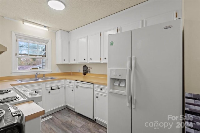 kitchen featuring sink, hardwood / wood-style floors, a textured ceiling, white appliances, and white cabinets