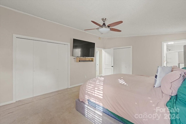 carpeted bedroom with a textured ceiling, ceiling fan, and multiple closets