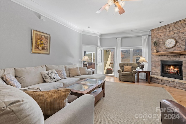 living room with a stone fireplace, light hardwood / wood-style flooring, ornamental molding, and ceiling fan