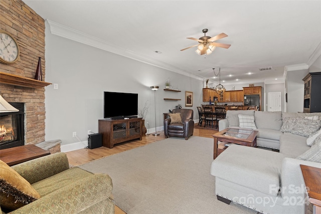 living room with a large fireplace, crown molding, light wood-type flooring, and ceiling fan