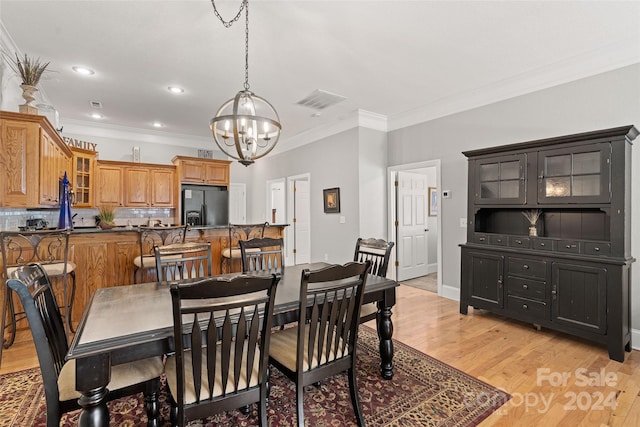 dining room featuring crown molding, light hardwood / wood-style flooring, and a notable chandelier