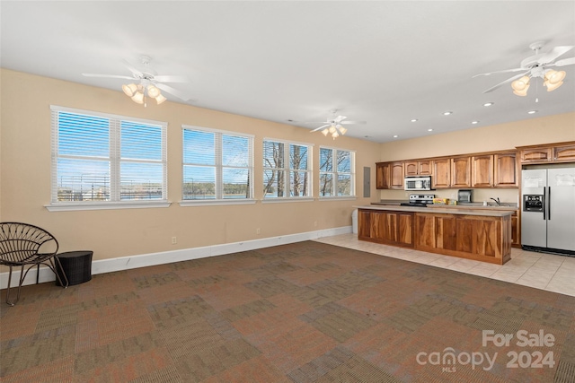 kitchen with ceiling fan, stainless steel appliances, a center island, and light colored carpet