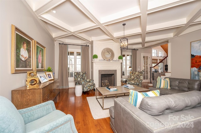 living room with coffered ceiling, an inviting chandelier, hardwood / wood-style flooring, and beamed ceiling