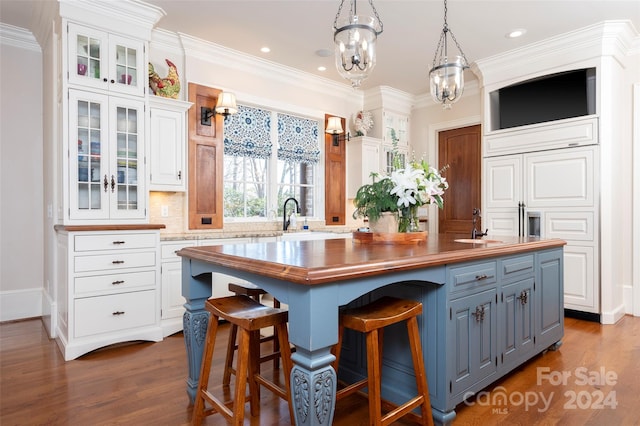 kitchen with dark wood-type flooring, a kitchen island, white cabinetry, and pendant lighting