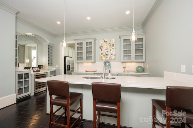 kitchen featuring stainless steel fridge with ice dispenser, pendant lighting, sink, a kitchen breakfast bar, and dark wood-type flooring