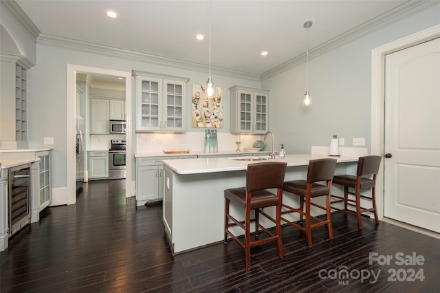 kitchen with appliances with stainless steel finishes, dark wood-type flooring, sink, and decorative light fixtures