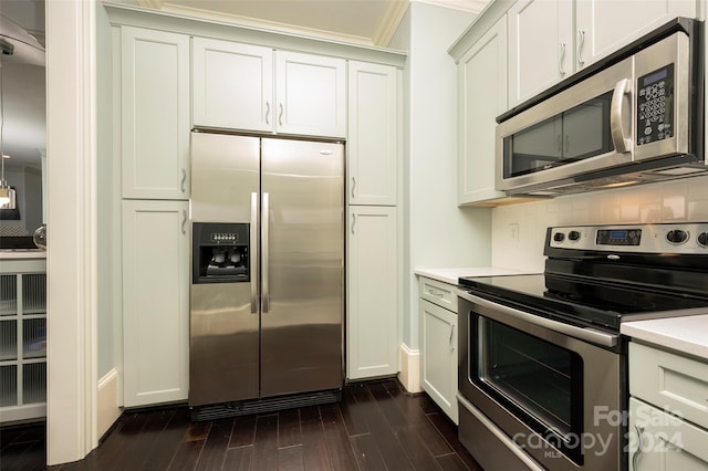 kitchen with stainless steel appliances, white cabinets, dark hardwood / wood-style floors, crown molding, and backsplash