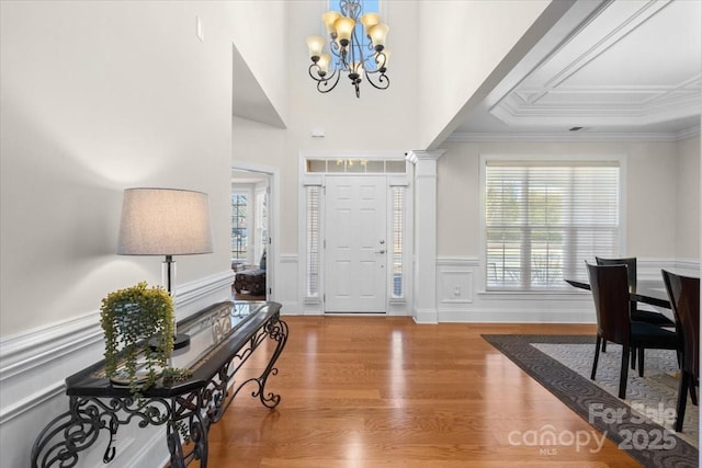 foyer entrance featuring ornamental molding, wood-type flooring, a chandelier, and a wealth of natural light