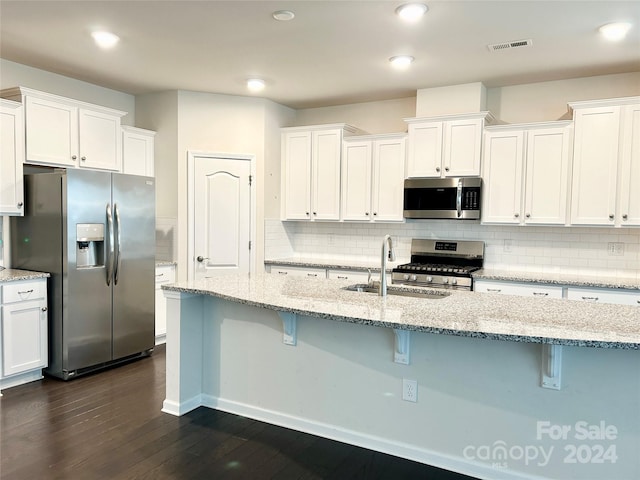 kitchen featuring a kitchen breakfast bar, stainless steel appliances, white cabinetry, and sink