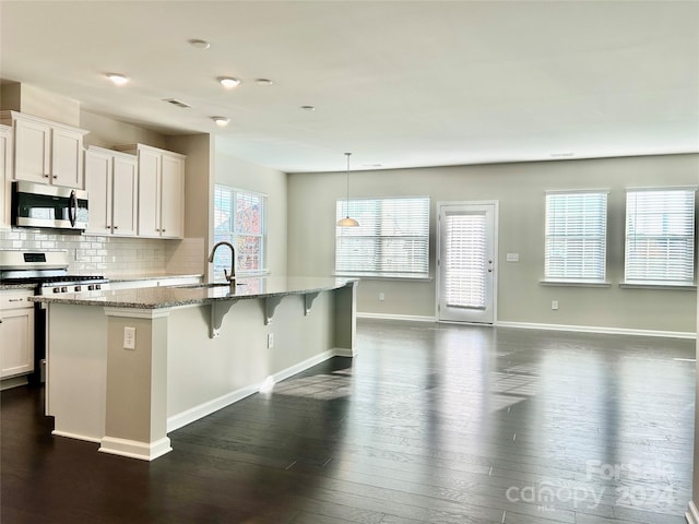 kitchen with white cabinetry, an island with sink, hanging light fixtures, and appliances with stainless steel finishes