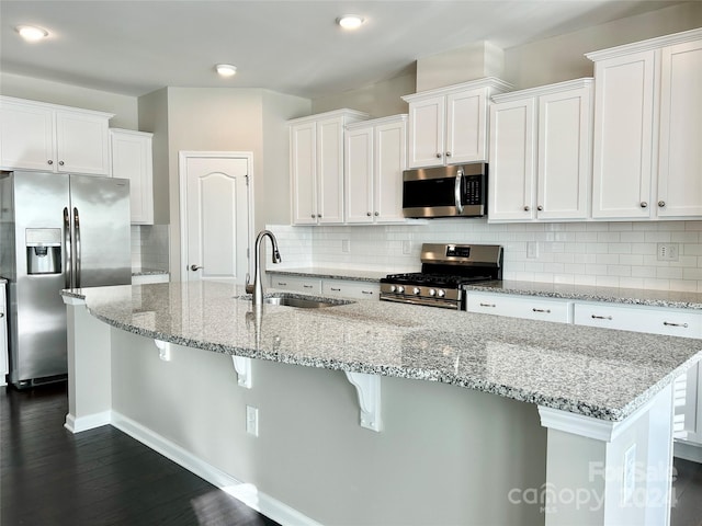 kitchen with dark wood-type flooring, sink, decorative backsplash, white cabinetry, and stainless steel appliances