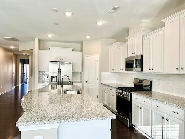 kitchen with white cabinetry, sink, stainless steel appliances, dark hardwood / wood-style flooring, and an island with sink