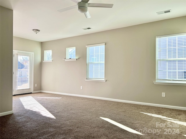 carpeted spare room with a wealth of natural light and ceiling fan