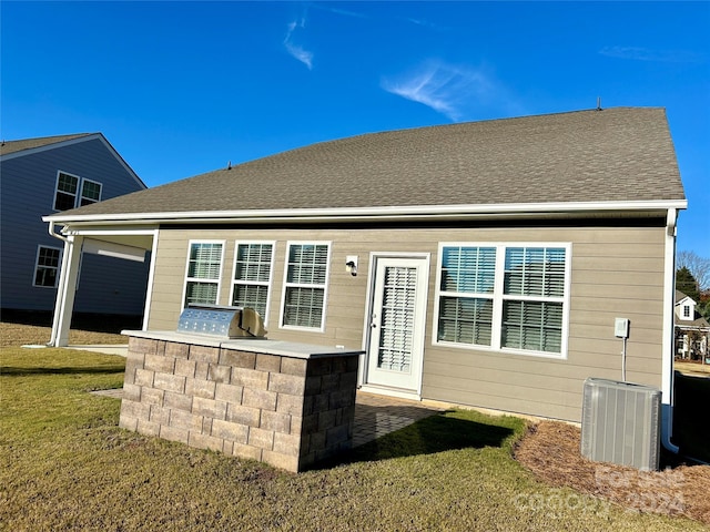 rear view of property with area for grilling, a yard, and central AC