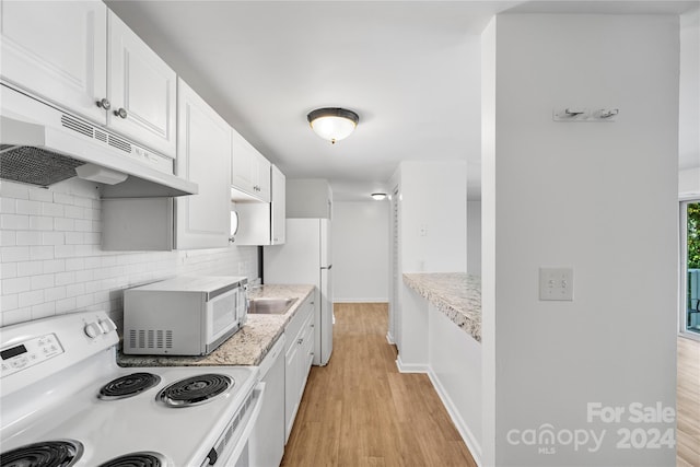 kitchen featuring white appliances, light stone countertops, white cabinetry, light hardwood / wood-style floors, and decorative backsplash