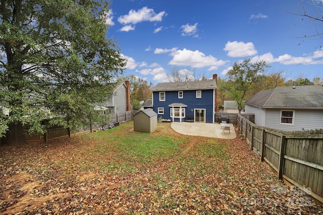 back of house featuring a lawn, a patio area, and a storage shed