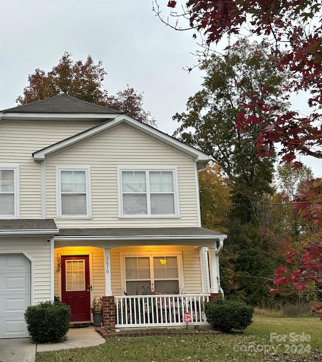 view of front facade featuring covered porch, a garage, and a front yard