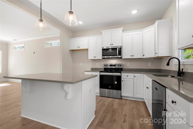 kitchen with appliances with stainless steel finishes, white cabinetry, pendant lighting, and sink