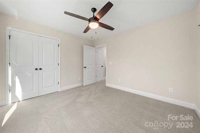 unfurnished bedroom featuring ceiling fan, a closet, and light carpet