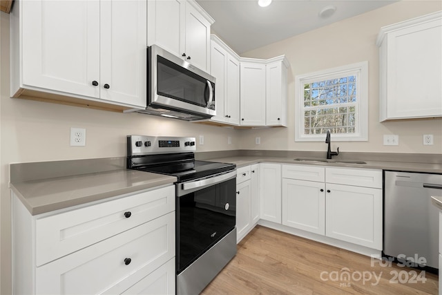 kitchen with light hardwood / wood-style floors, sink, white cabinetry, and stainless steel appliances