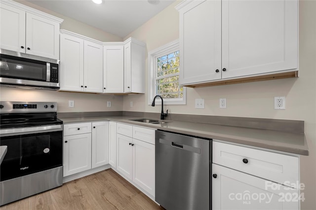 kitchen featuring white cabinetry, sink, stainless steel appliances, and light hardwood / wood-style flooring