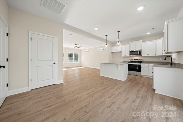 kitchen featuring appliances with stainless steel finishes, light wood-type flooring, white cabinets, a kitchen island, and hanging light fixtures