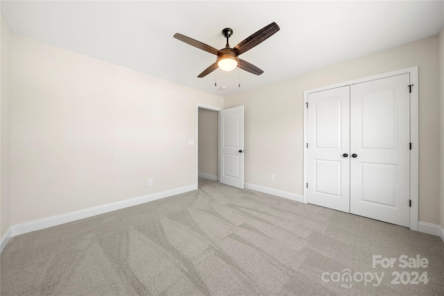 unfurnished bedroom featuring ceiling fan, light carpet, and a closet