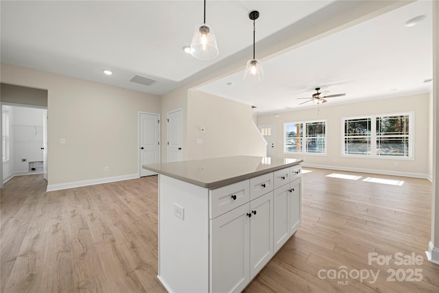 kitchen featuring a kitchen island, visible vents, white cabinetry, open floor plan, and decorative light fixtures