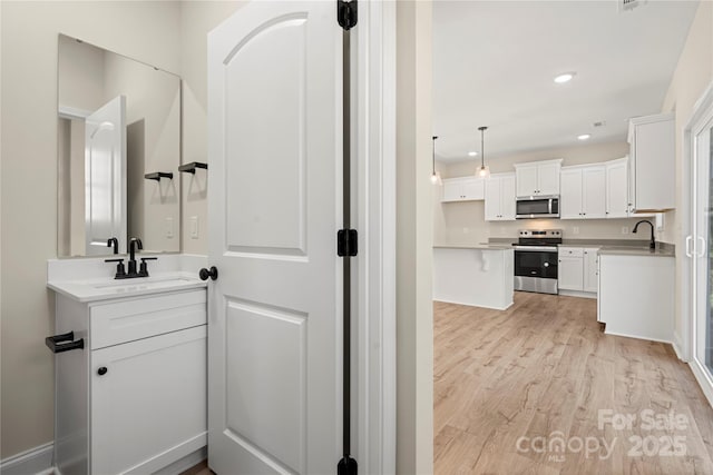 bathroom with recessed lighting, a sink, and wood finished floors