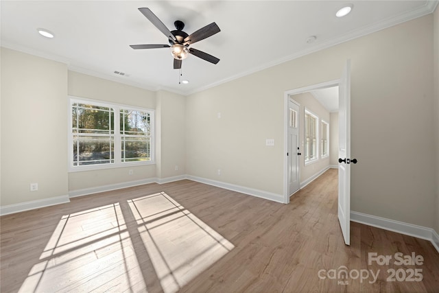 empty room featuring baseboards, crown molding, visible vents, and light wood-style floors