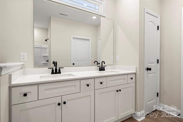 full bath with double vanity, baseboards, visible vents, and a sink