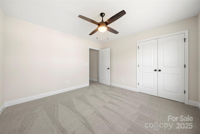 unfurnished bedroom featuring a ceiling fan, baseboards, a closet, and light colored carpet